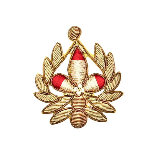 An embroidered emblem featuring a gold-tone laurel wreath with a central fleur-de-lis design in gold and red, finished with a small white pearl at the center, shown on a plain white background.