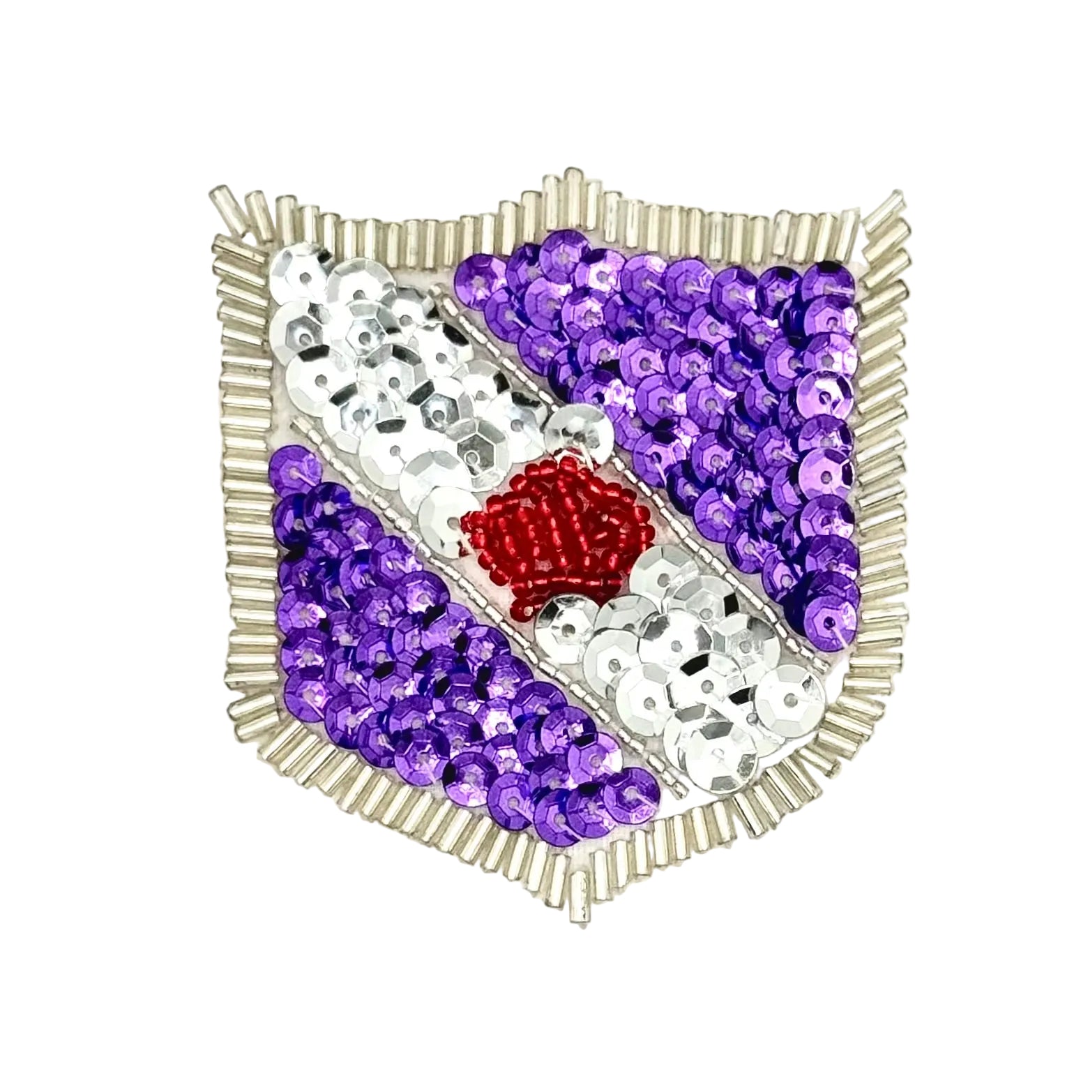 A shield-shaped decorative patch or brooch made of purple and silver sequins with a small red sequin center, shown on a plain white background.