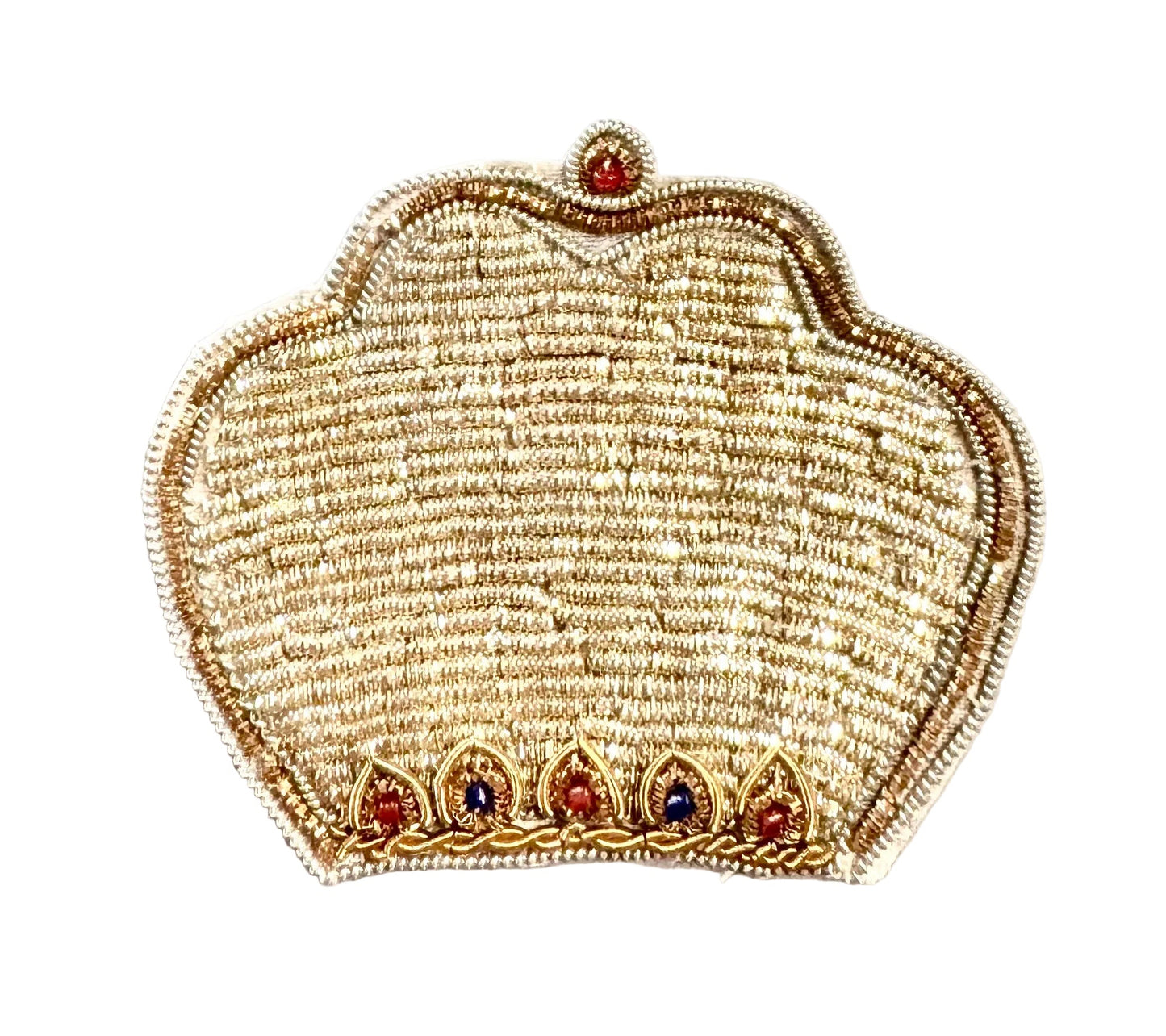 An embroidered patch shaped like a traditional Indian crown, featuring intricate gold and beige threadwork with small red and blue jewel accents, placed on a light-colored surface.