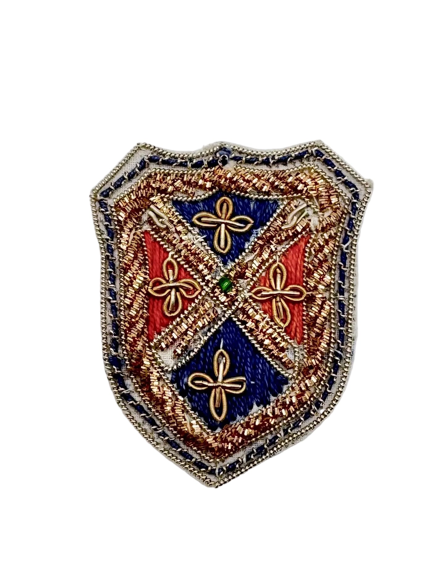An ornate shield-shaped embroidered patch featuring a heraldic design with blue, red, and gold sections, four gold floral motifs, and a small green center stone on a plain white background.