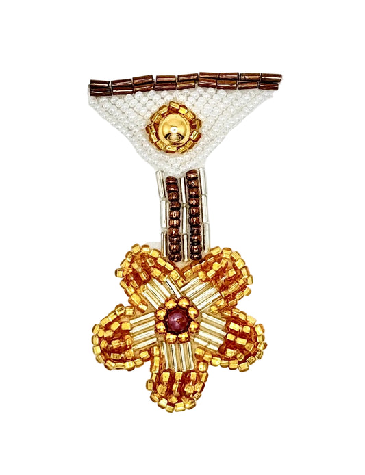 A handcrafted beaded medal motif featuring a large gold and brown flower with a central purple jewel, attached to a white beaded triangle with brown accents, photographed on a plain white background.