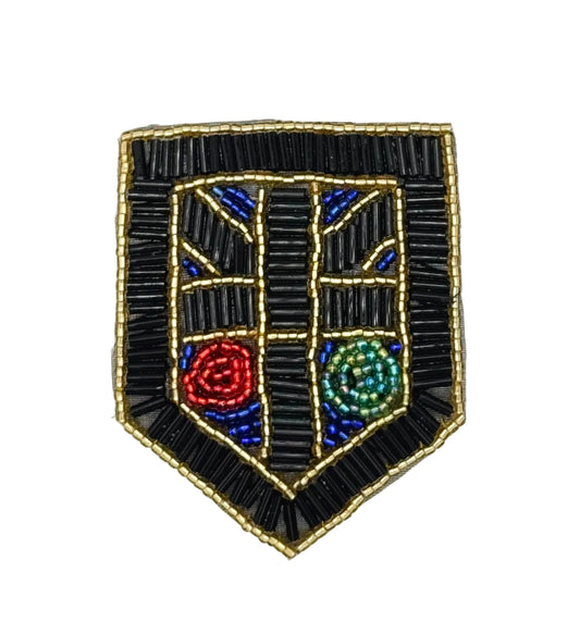 A shield-shaped beaded patch with a black beaded border and central design, featuring blue geometric accents and two circular motifs in red and green, on a plain white background.