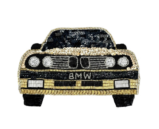 A sequin patch of a classic BMW car, featuring black and gold sequins with silver sequin headlights and 'BMW' lettering on the front grille, set against a plain white background.