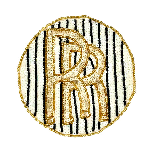 A circular sequin and bead vintage patch featuring a large interlocking gold monogram over vertical black and white stripes, finished with a gold border on a white background.