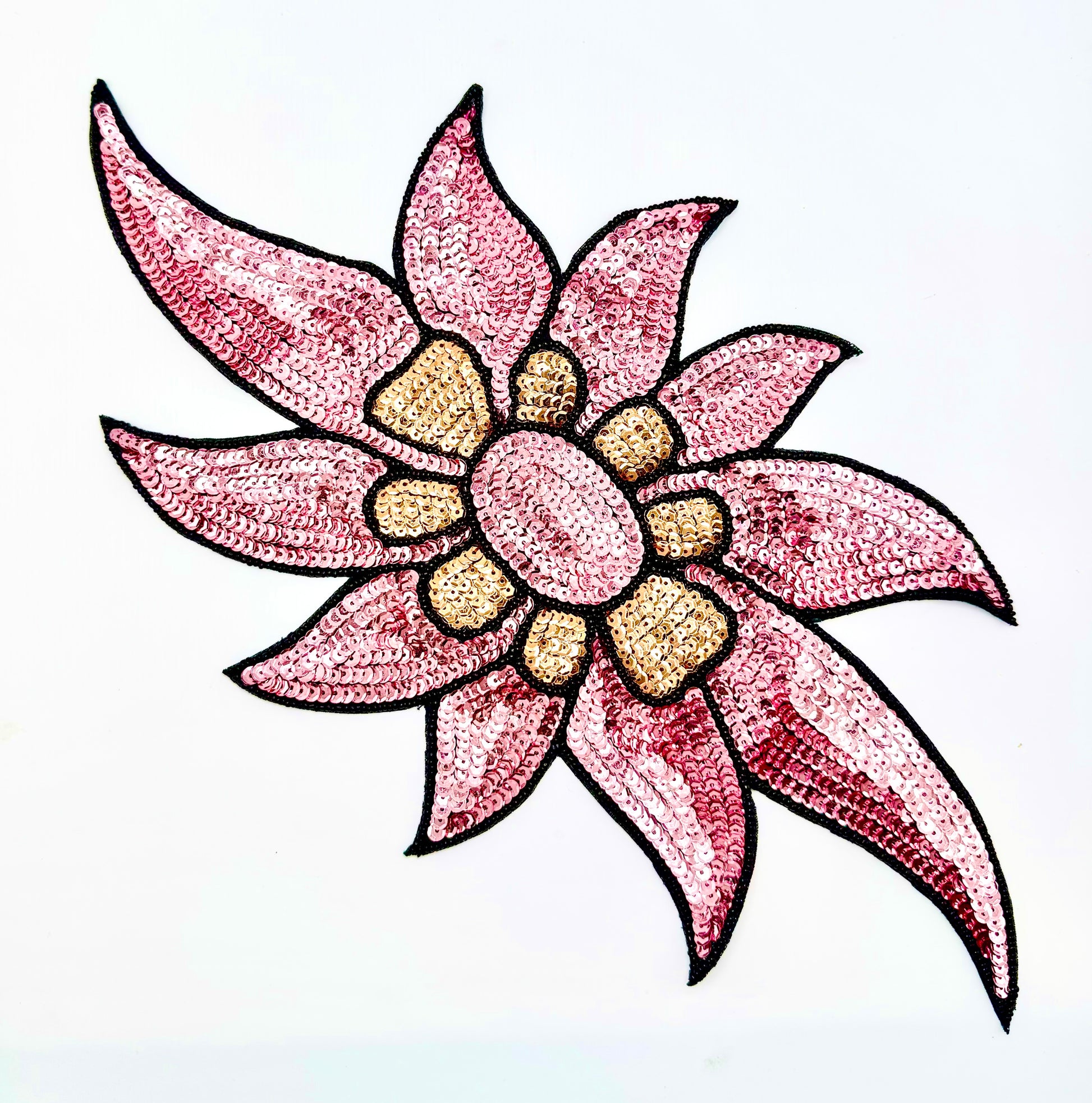 A stylized sequined flower motif with pink petals outlined in black, a pink center, and tan/golden center details on a plain white background.