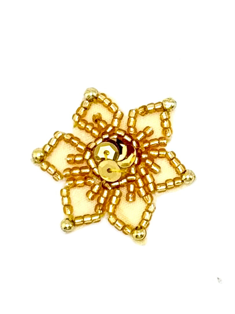 A gold beaded snowflake appliqué with intricate beaded detailing and central faceted sequins shown on a plain white background.
