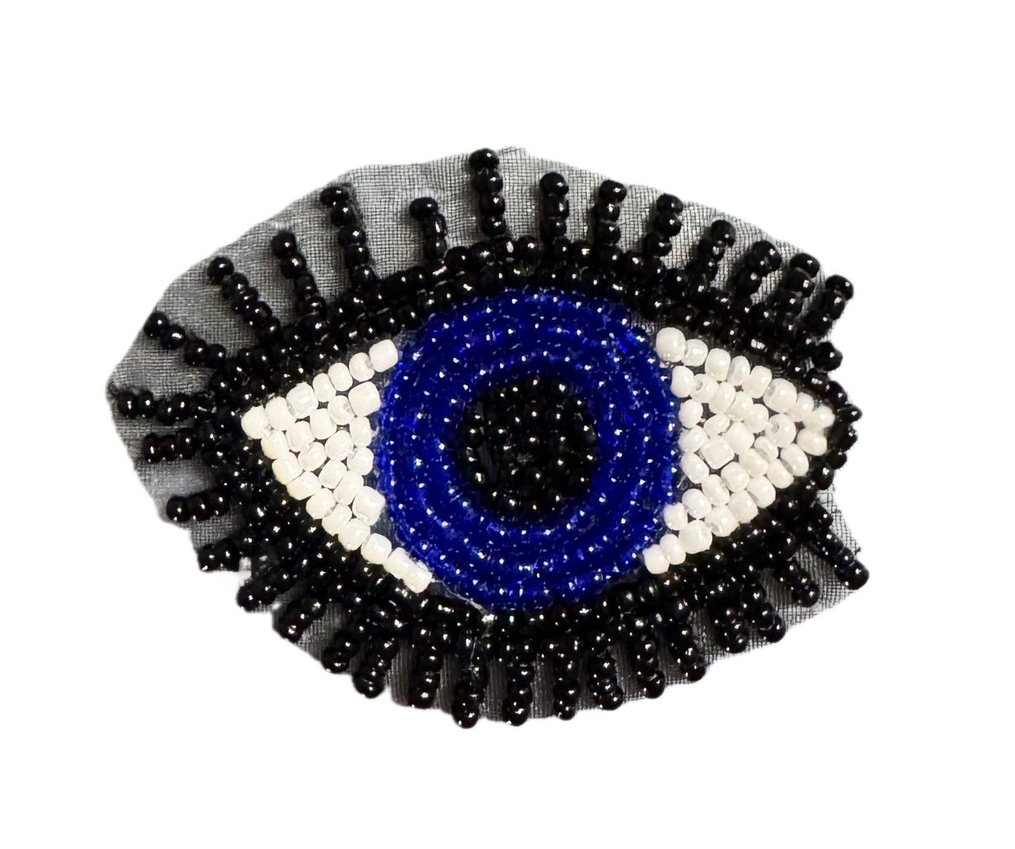 A beaded evil eye patch featuring a blue center, white and blue concentric rings, and black outer rays on a sheer gray fabric backing, shown against a plain white background.