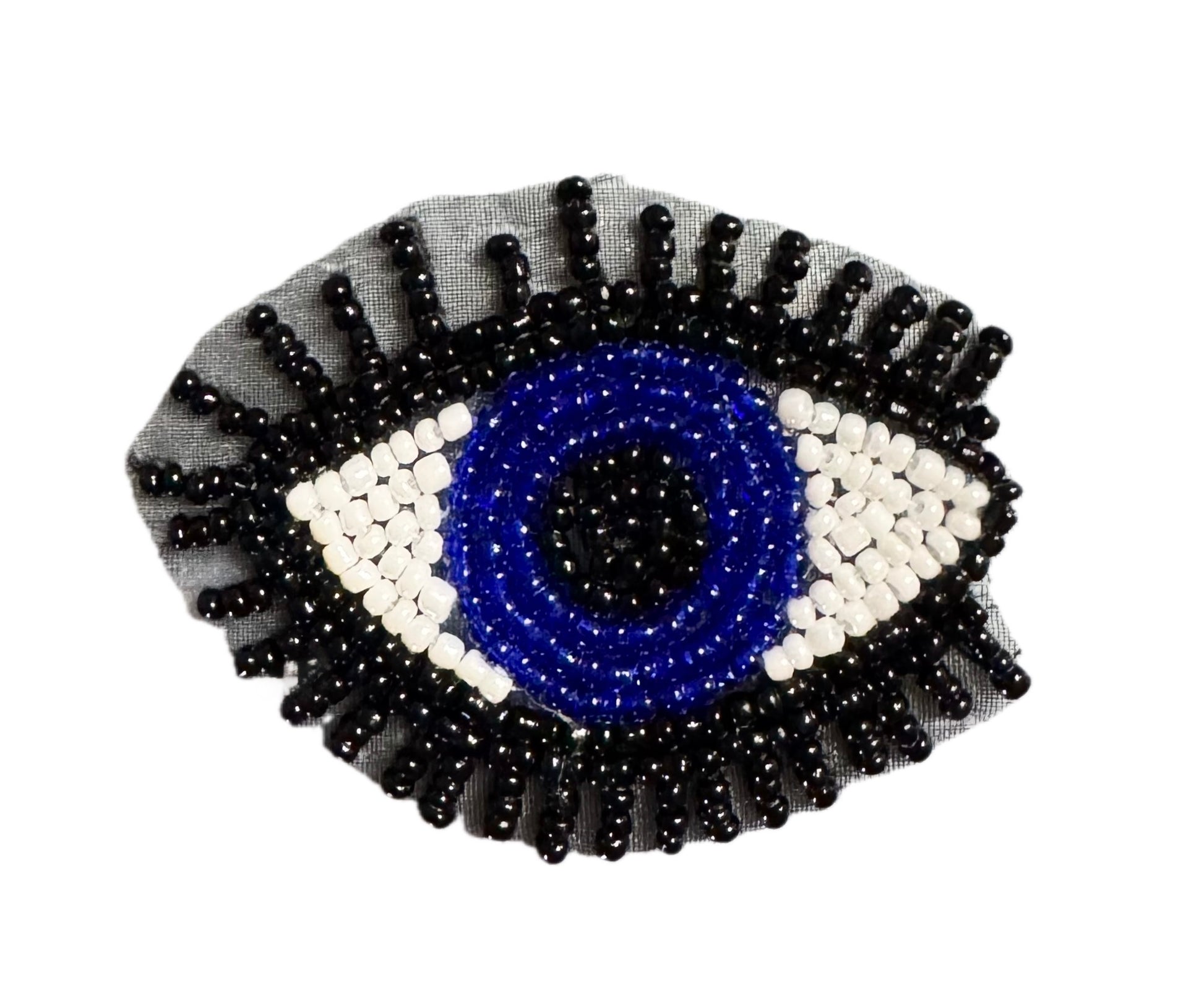 A beaded evil eye patch featuring a blue center, white and blue concentric rings, and black outer rays on a sheer gray fabric backing, shown against a plain white background.