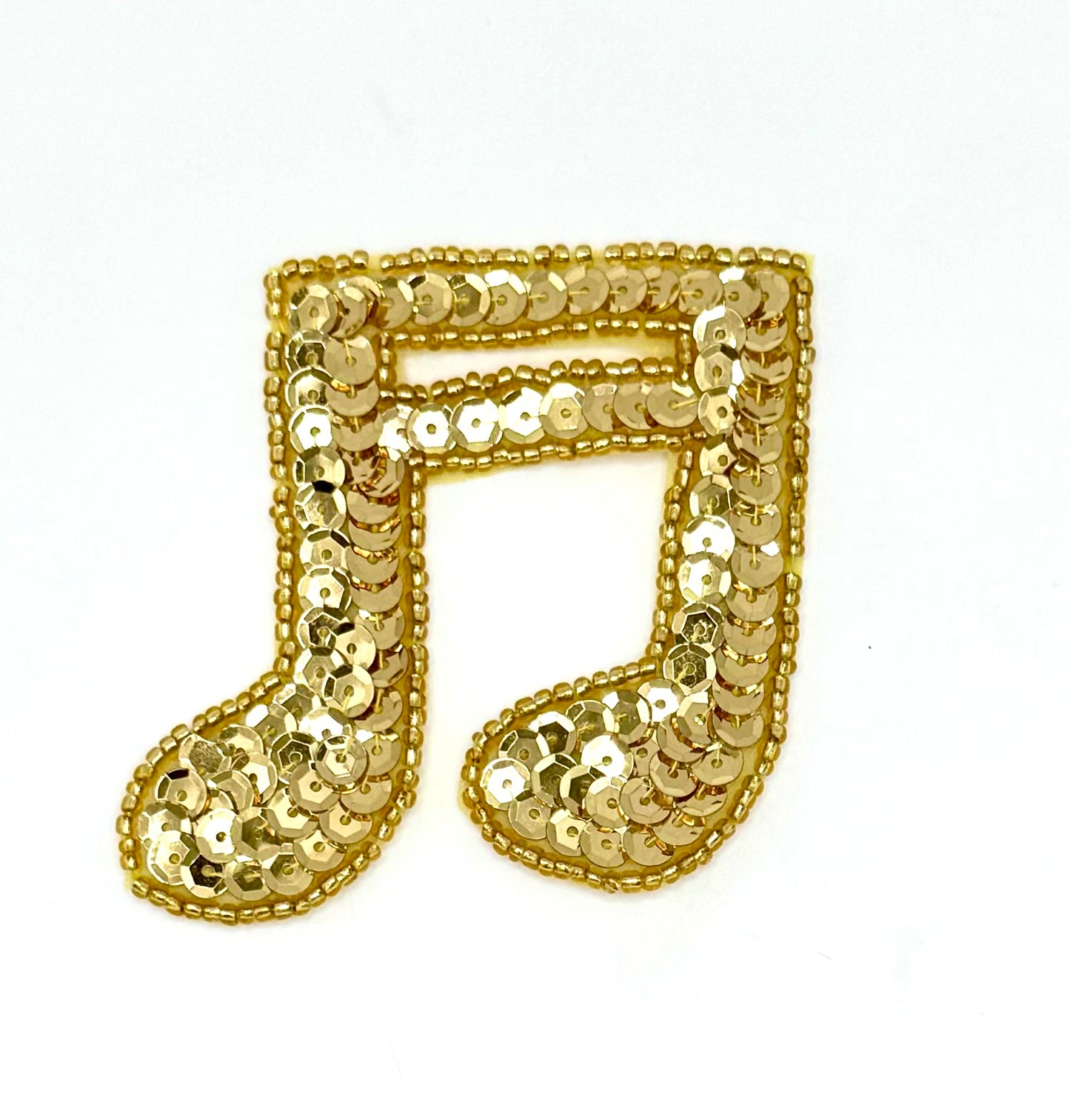 Gold sequin music note on a white background