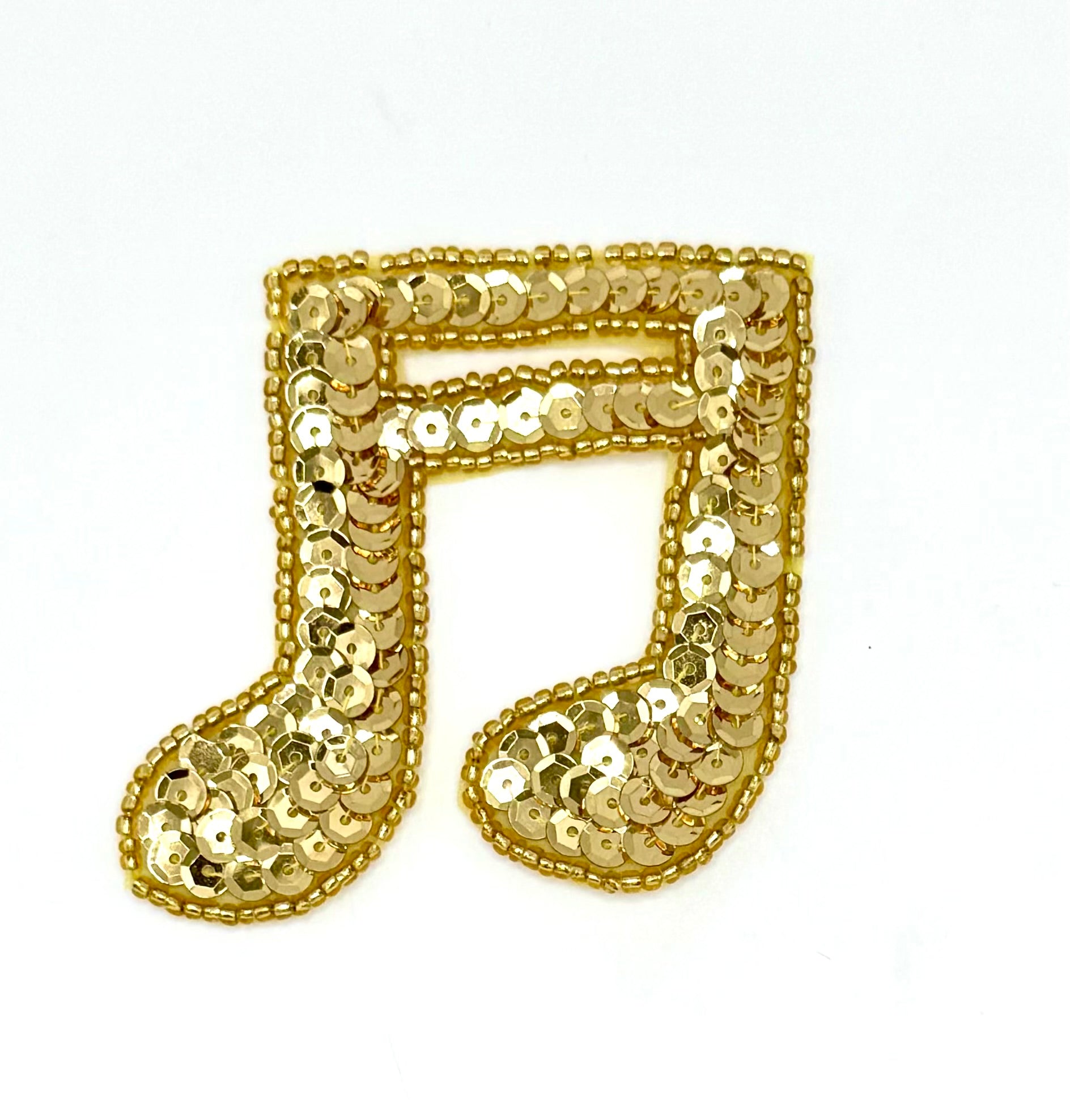 Gold sequin music note on a white background