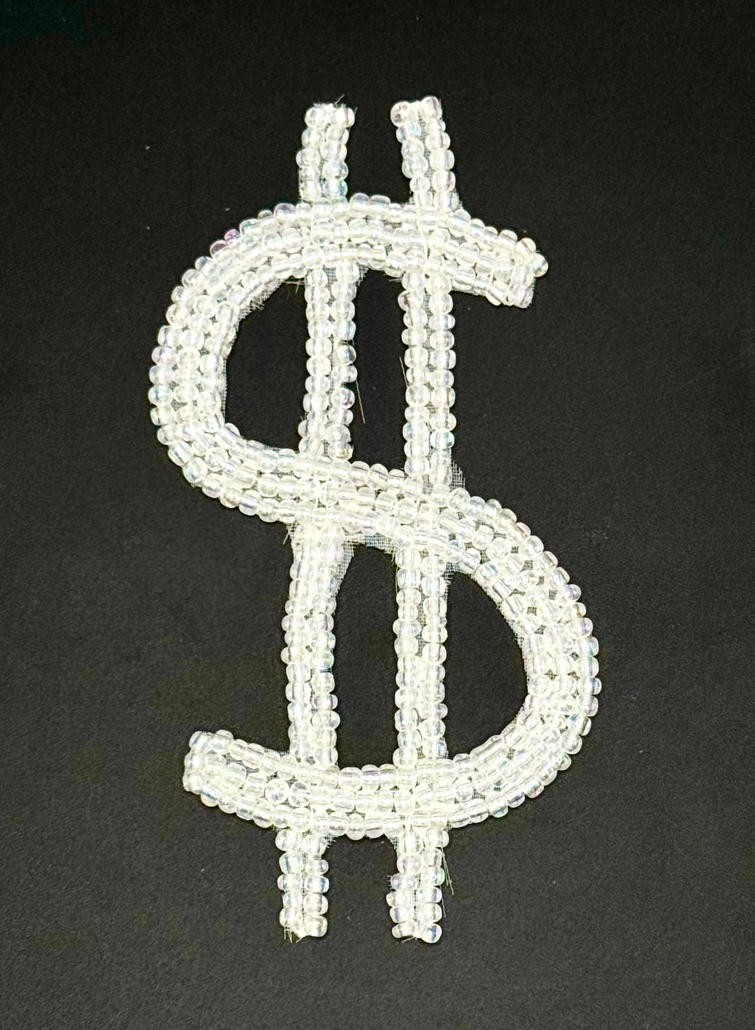 Dollar sign symbol made of white beads on a black background