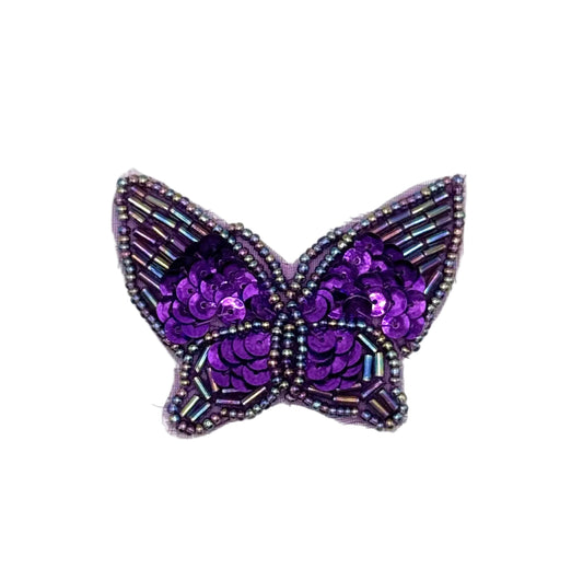 Purple butterfly-shaped decorative item with sequin and glass bead accents on a white background