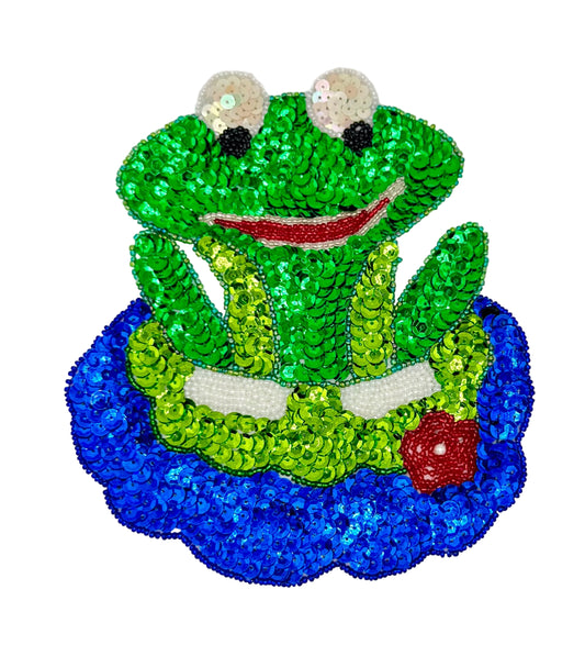 Sequined frog patch with green body, blue base, and red accents on a white background