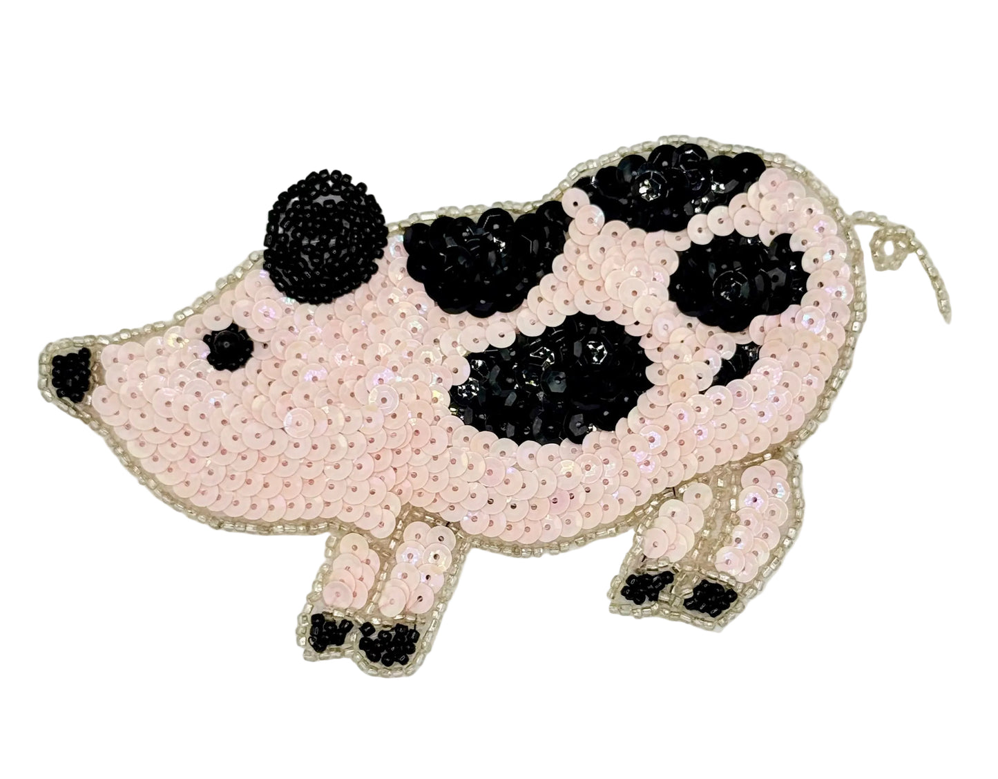 Pig-shaped pink patch with black sequin spots on a light gray background