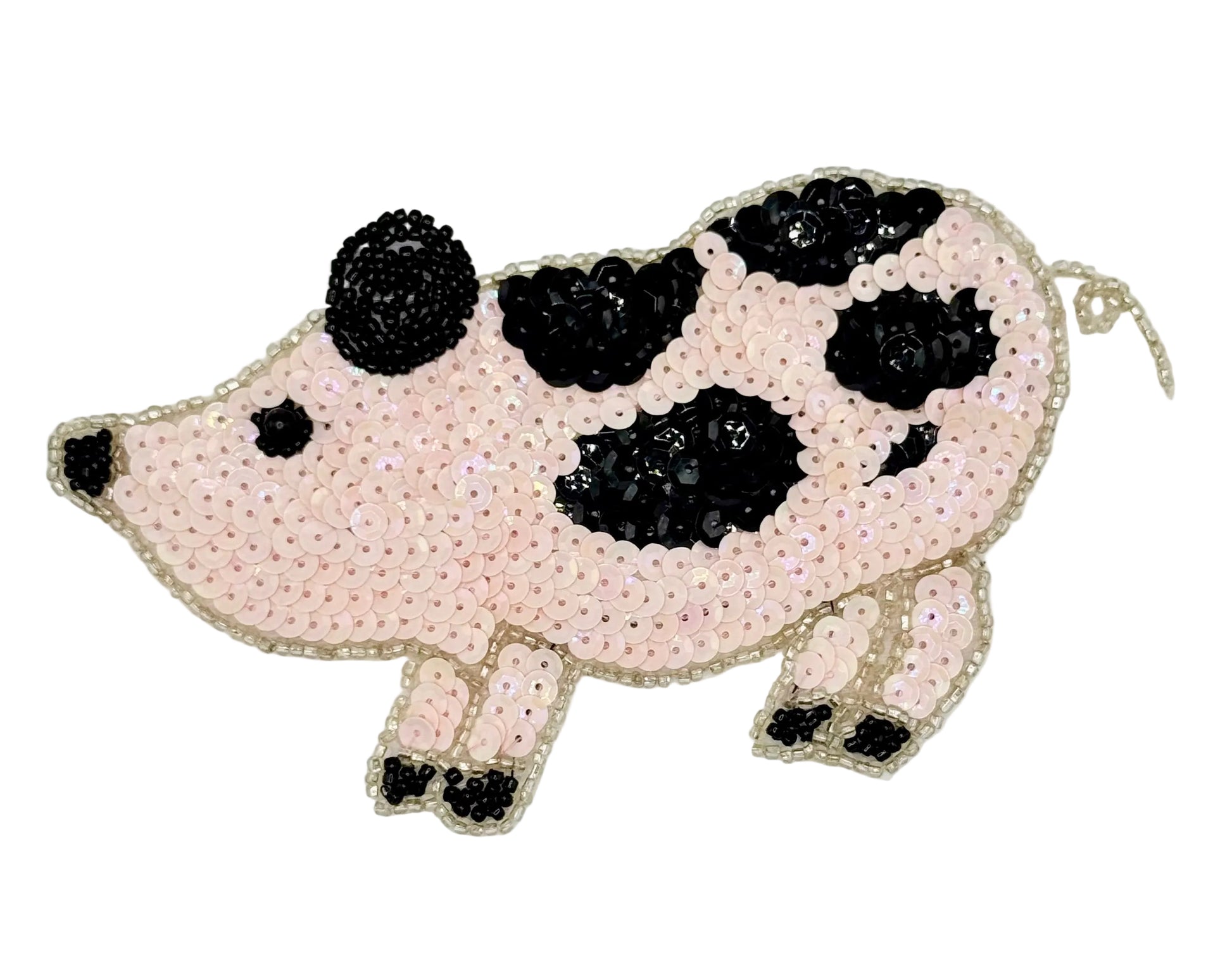 Pig-shaped pink patch with black sequin spots on a light gray background