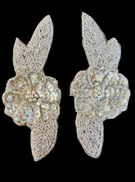 Pair of decorative floral embellishments with sequins on a black background