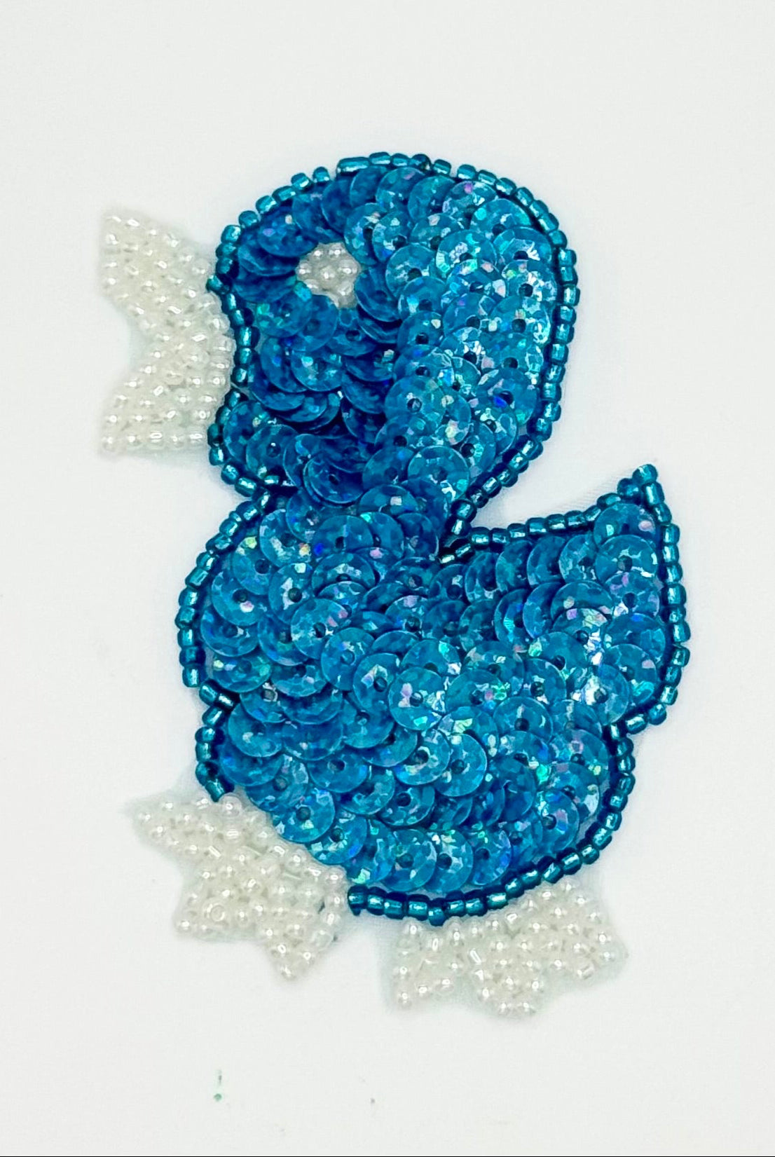 Blue sequin duckling with blue and white beads on a white background