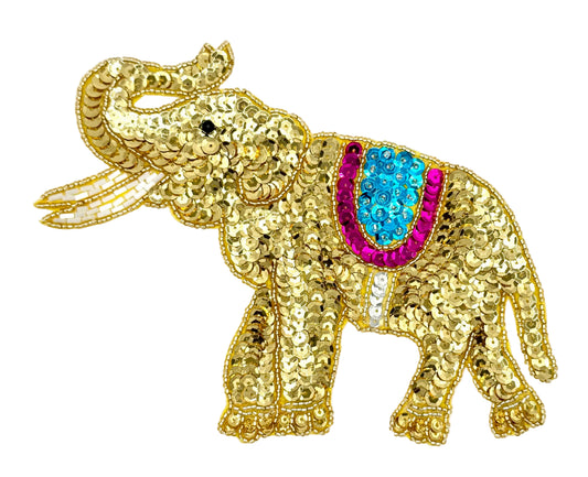 Gold sequined elephant with a turquoise and fuchsia saddle on a white background