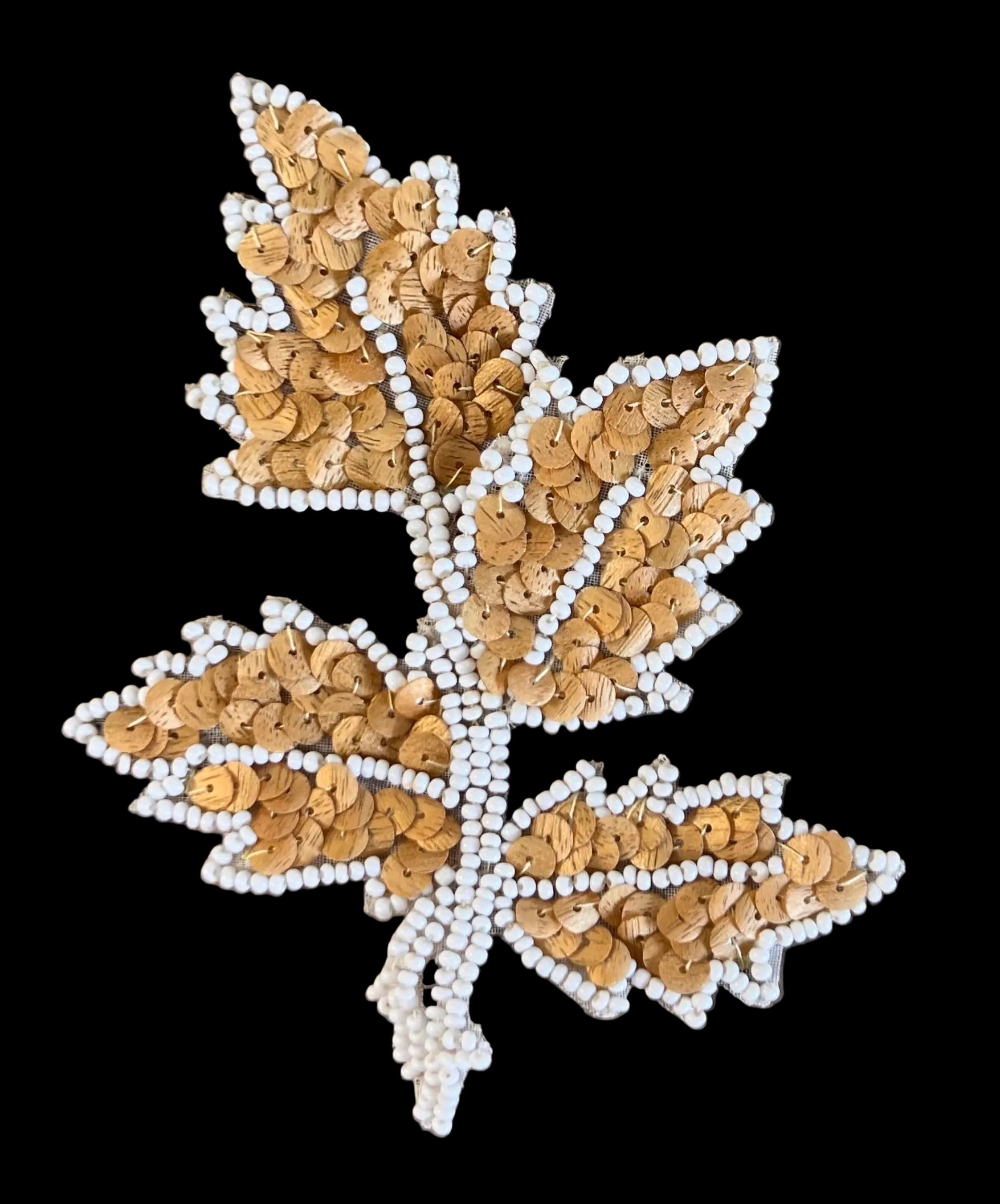 Decorative leaf design with sequins on a dark background