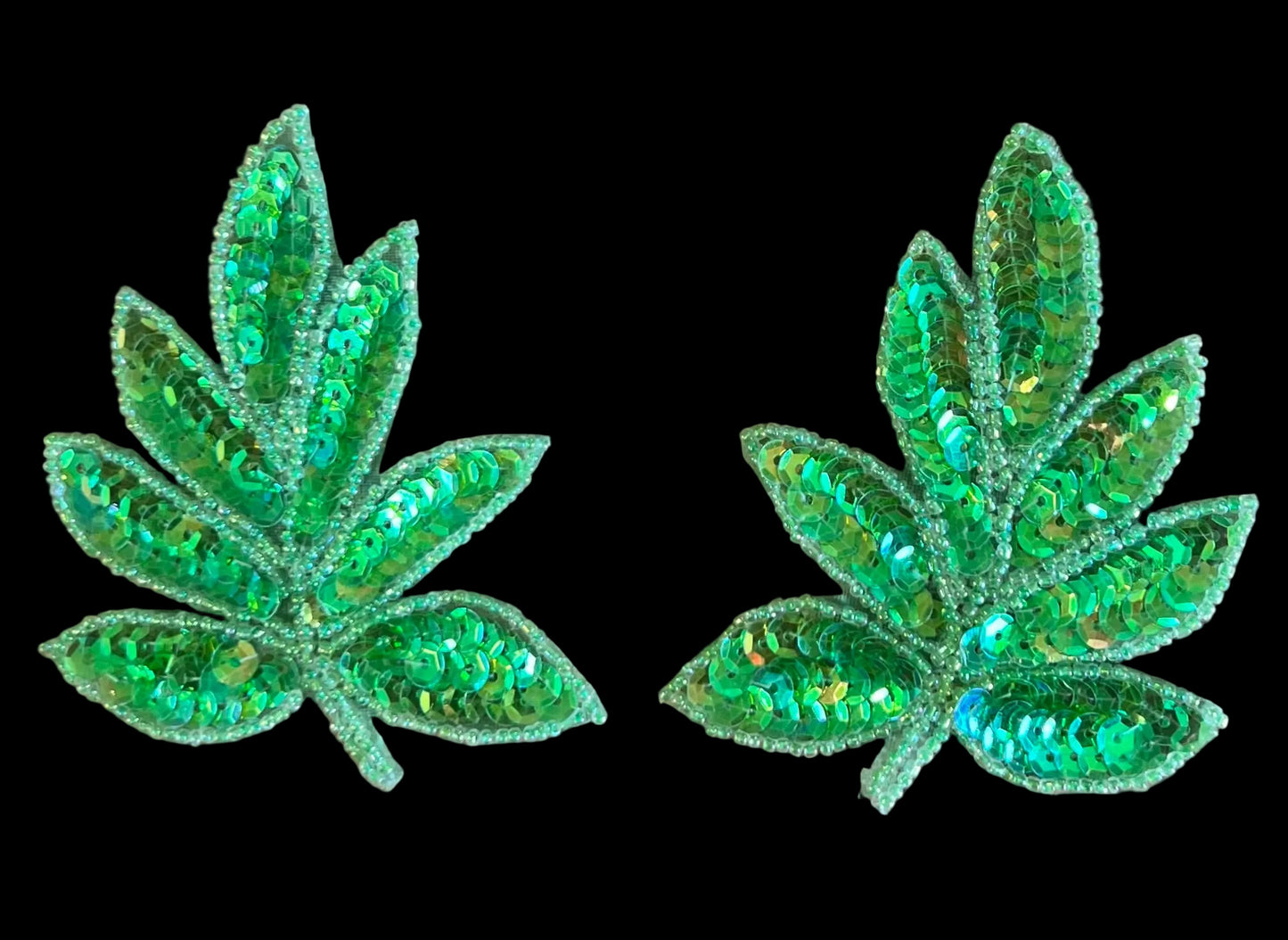 Two green sequin leaf patches on a brown dark background