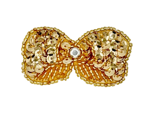 Gold bow with sequins and beads with a central grhinestone on a white background