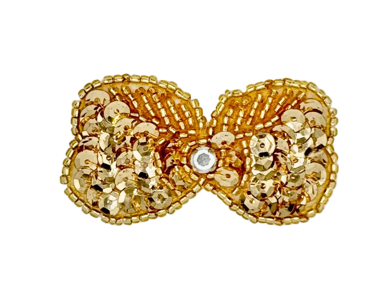 Gold bow with sequins and beads with a central grhinestone on a white background