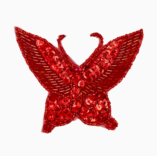 Red butterfly-shaped decorative item with sequins on a white background
