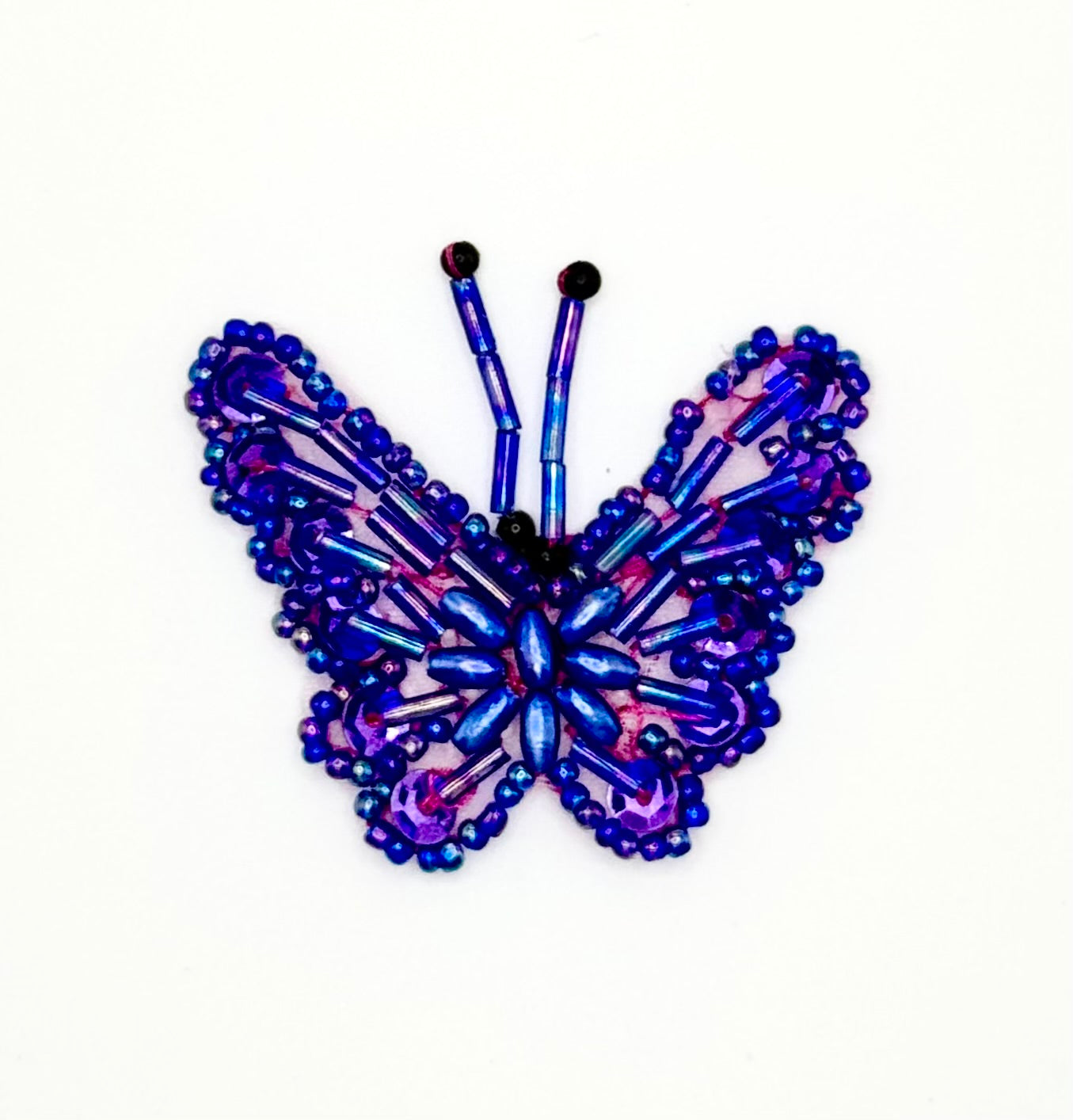 Butterfly-shaped patch with purple and blue sequins and beads on a white background