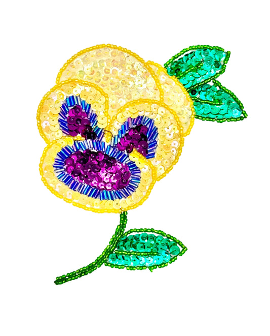 Sequin and bead patch with a yellow and purple flower and green leaves on a white background