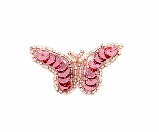 Butterfly-shaped sequin patch with pink sequins and beads on a white background
