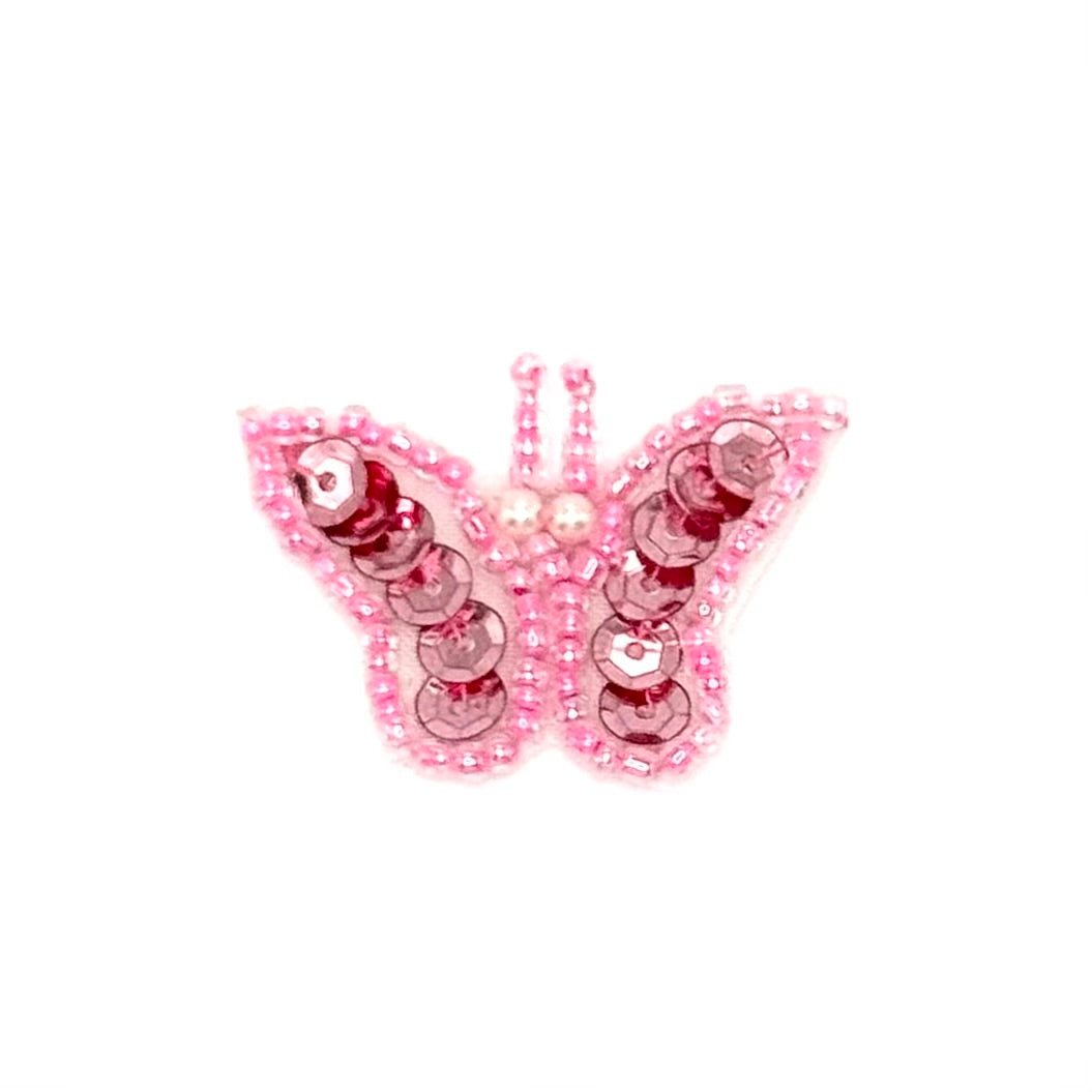 Pink butterfly decorative item with sequins on a white background