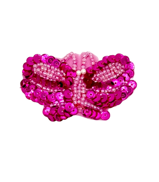 Pink butterfly-shaped patch with sequins on a white background
