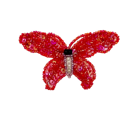 Red butterfly-shaped decorative item with beads on a white background