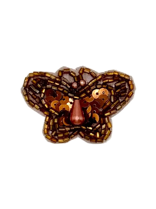 Butterfly-shaped sequin and bead patch with bronze colors on a white background