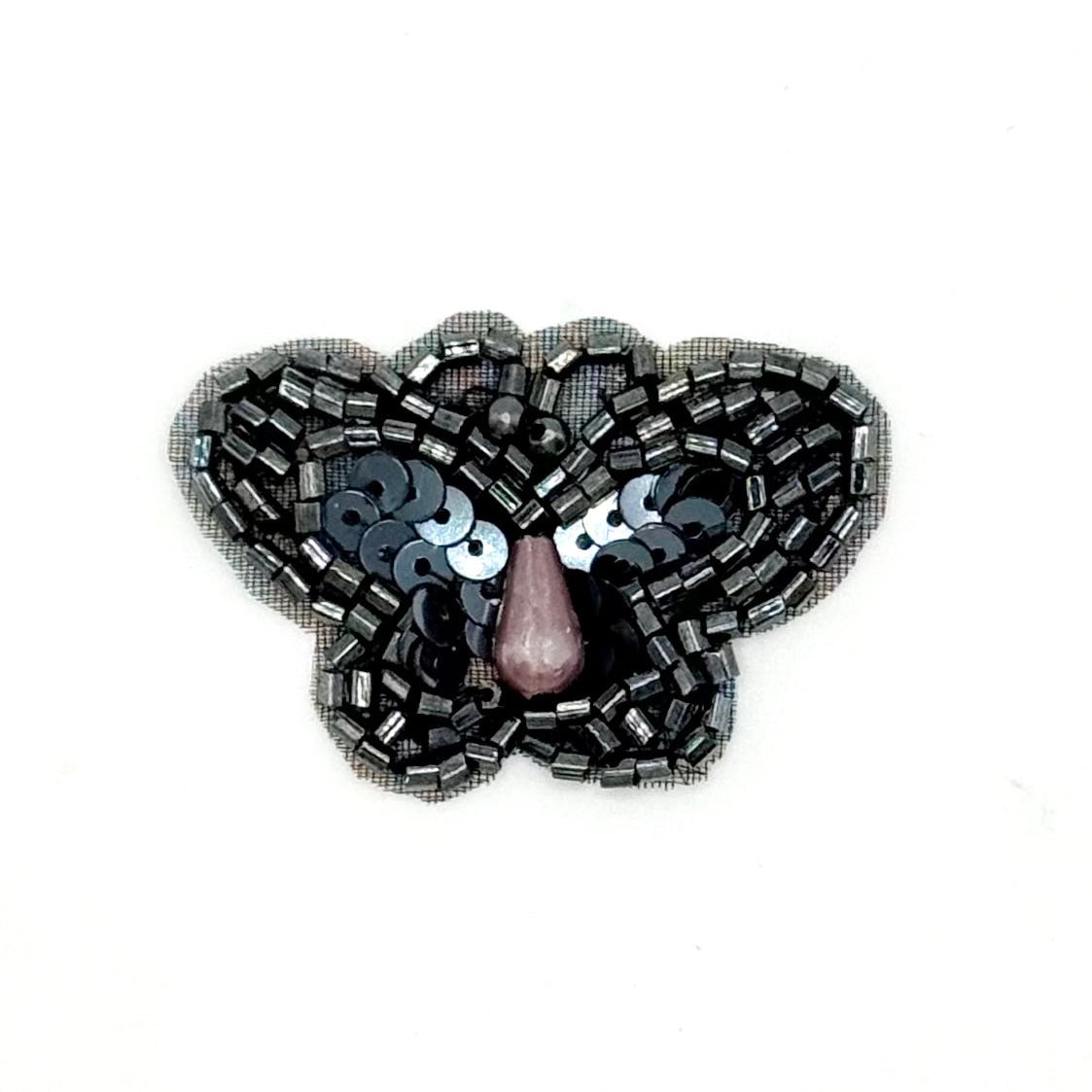 Sequin gunmetal colored butterfly-shaped brooch with sequins on a white background