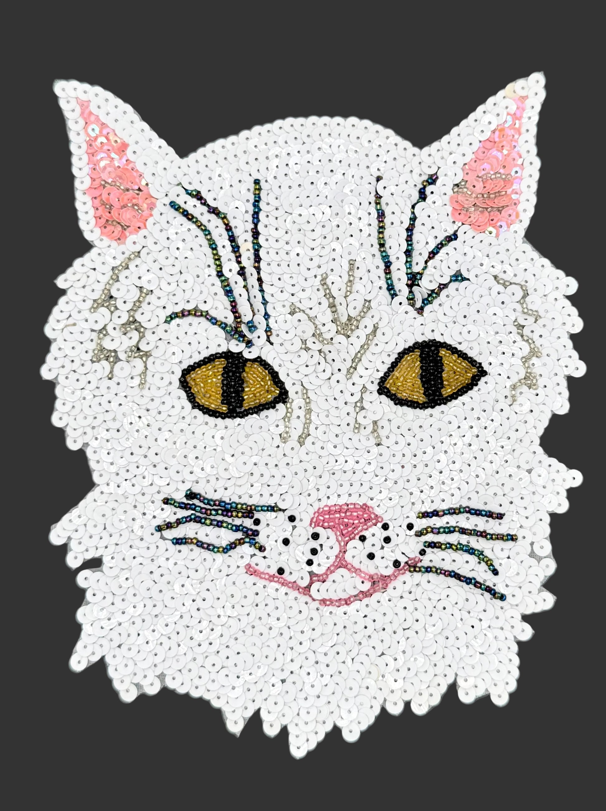 White sequin cat face with sequins and beads on a dark background