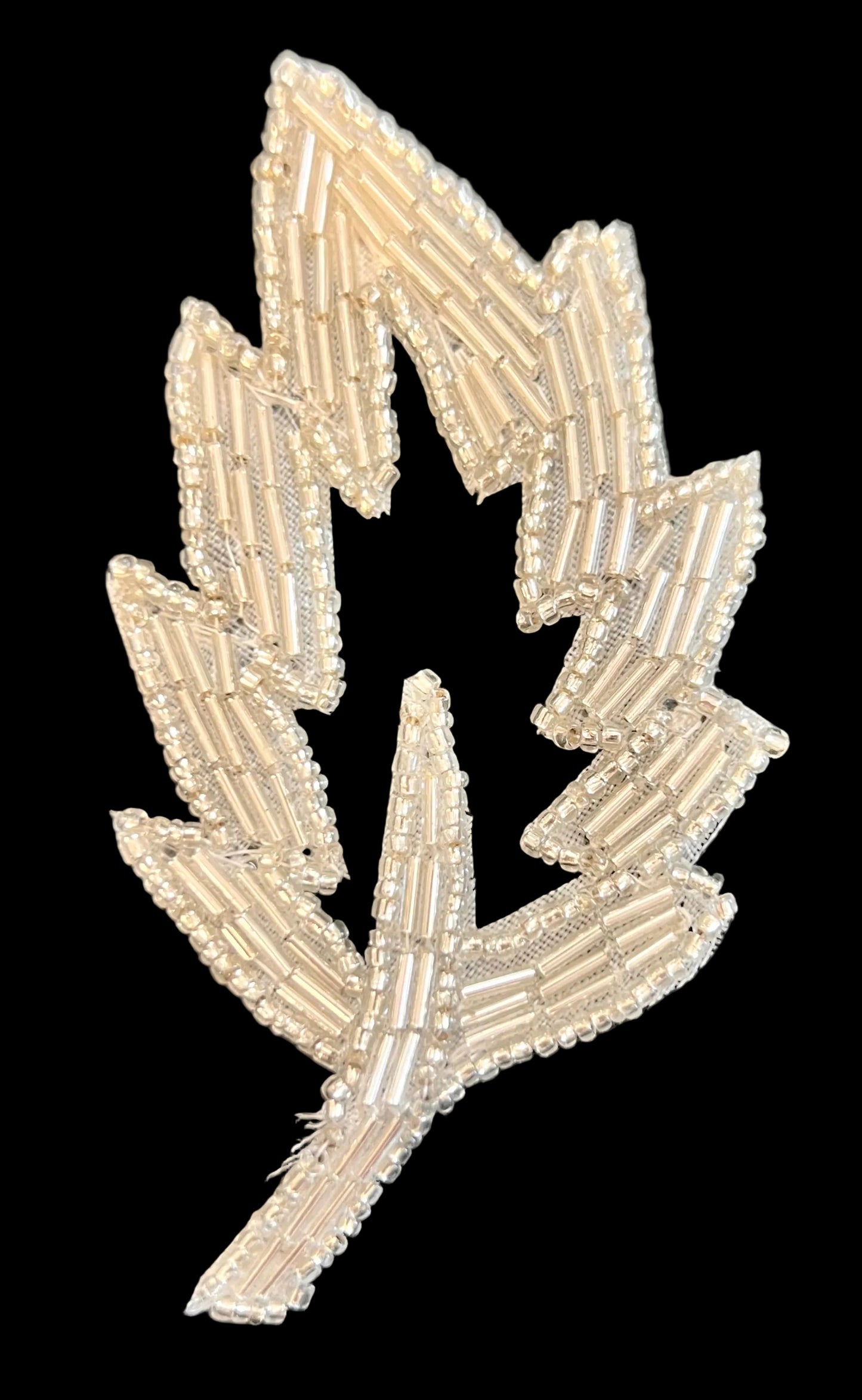 Decorative leaf-shaped patch with beaded design on a black background