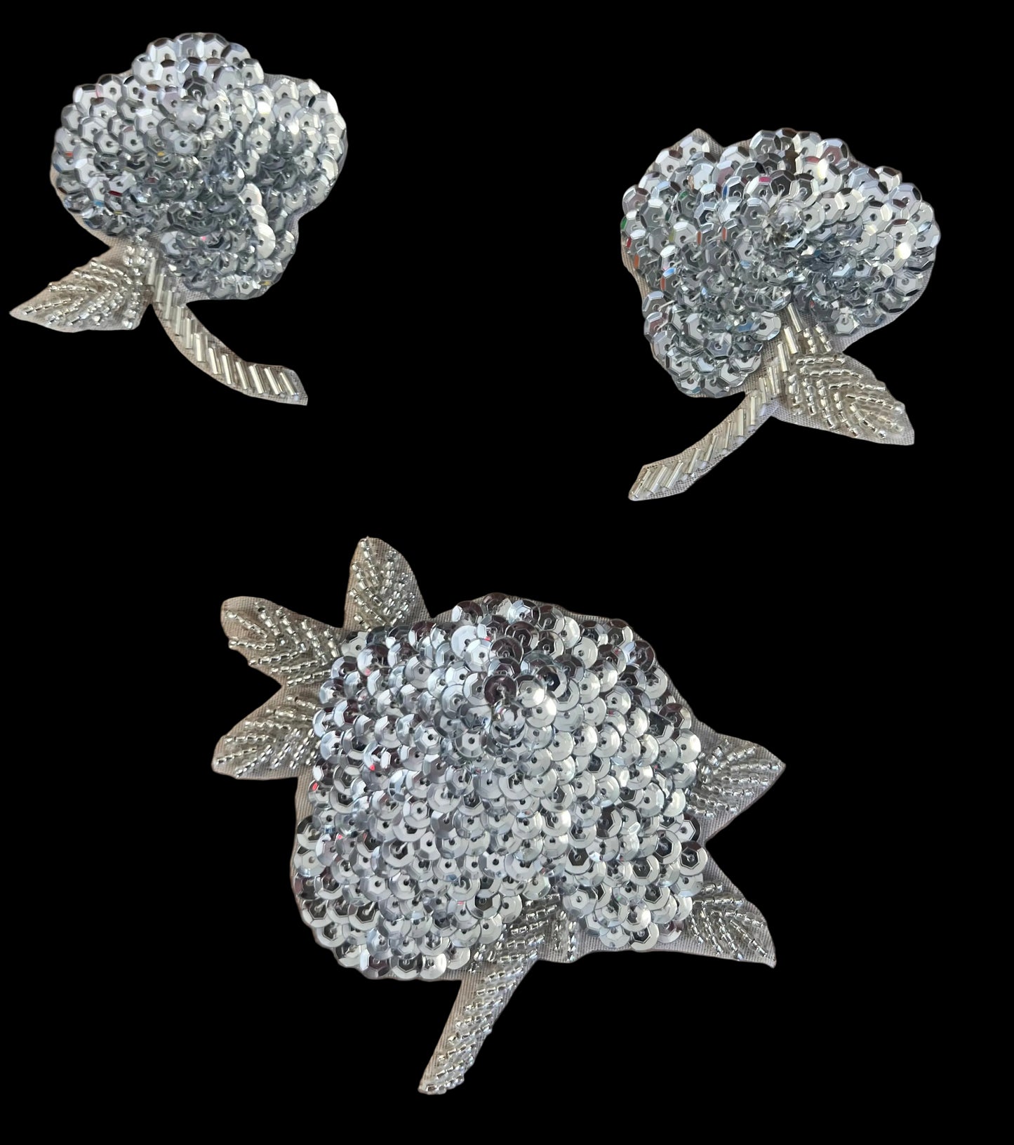 Three silver sequin flower patches on a dark background