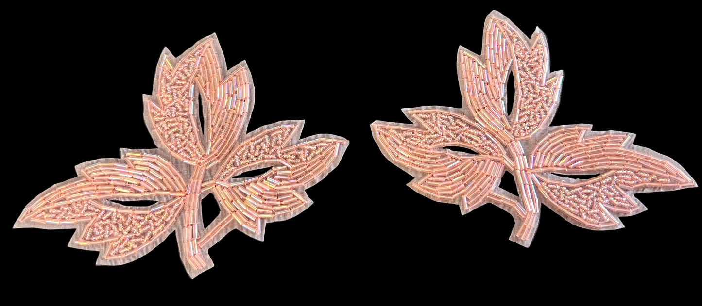 Two leaf-shaped beaded decorative items with intricate patterns on a dark background