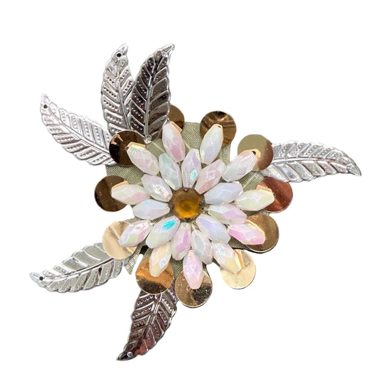 A floral appliqué with iridescent white and pink petals, a gold-toned center, and silver-toned leaf accents, displayed on a white background.