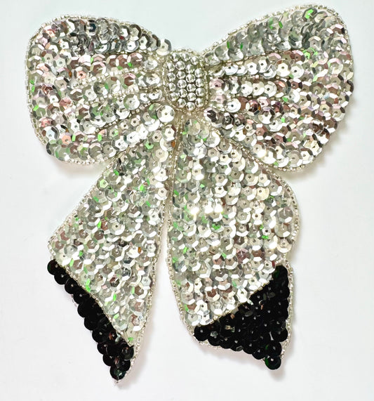 Silver sequin bow with black accents on a white background