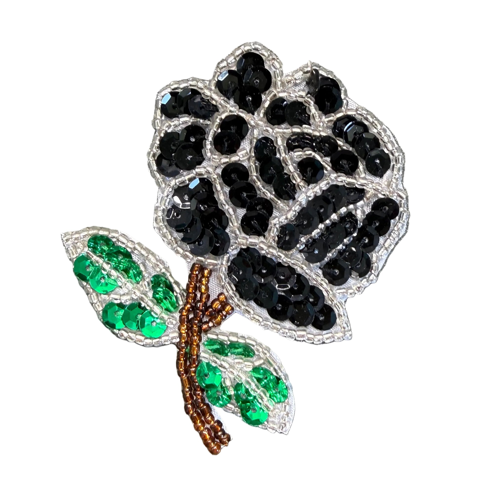 A small embroidered floral patch featuring a black sequined rose with two green sequined leaves and a brown stem, placed on a white surface.