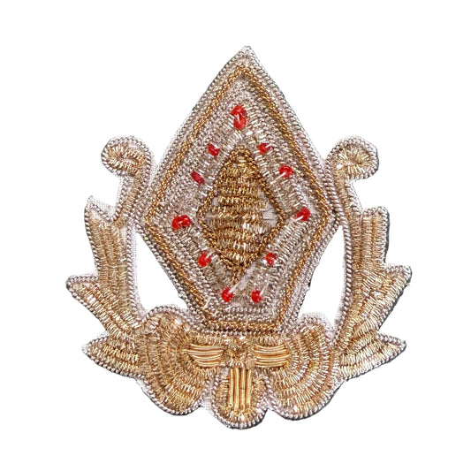 A decorative embroidered patch featuring a diamond-shaped central motif with red bead accents and ornate side scroll details.