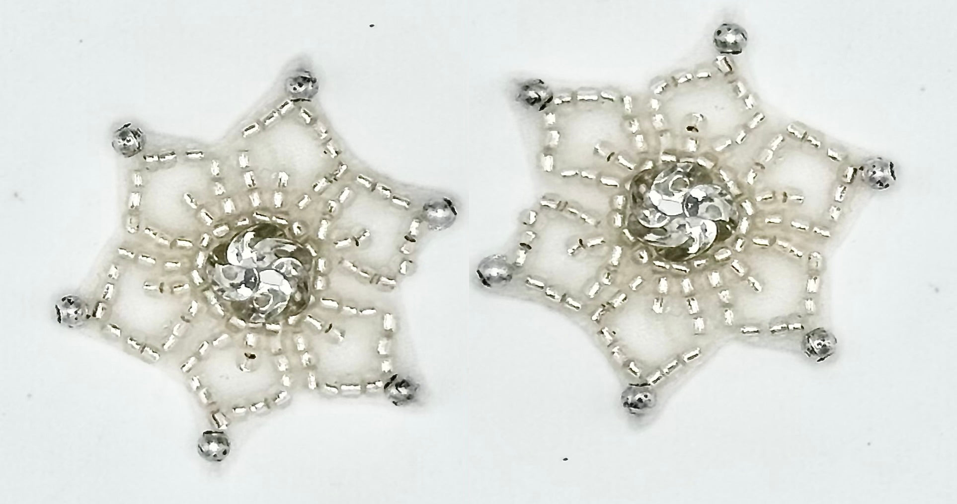Two silver beaded snowflake-shaped patches with silver sequin centers, displayed on a plain white background.