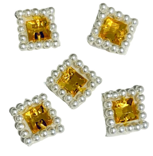 Five square decorative embellishments featuring a central square yellow crystal surrounded by a border of small white faux pearls on a silver backing, shown on a plain white background.